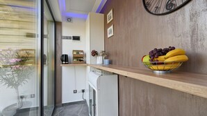 Een moderne keuken met een houten aanrecht, een koffieapparaat, een mand met fruit en een klok aan de muur.