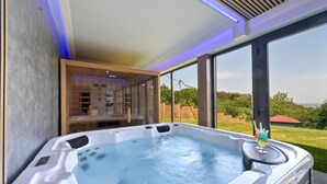 Een bubbelbad met glazen wanden, een houten plank en uitzicht op de omgeving.