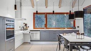 Una cucina moderna con una grande finestra, elettrodomestici integrati e un'area pranzo con sedie.