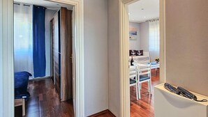 Un pasillo que conduce a un comedor con una mesa y sillas, una cortina azul y piso de madera.