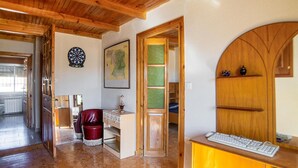 A room with a wooden ceiling, a dartboard, a map, a desk with a keyboard, and a red chair.