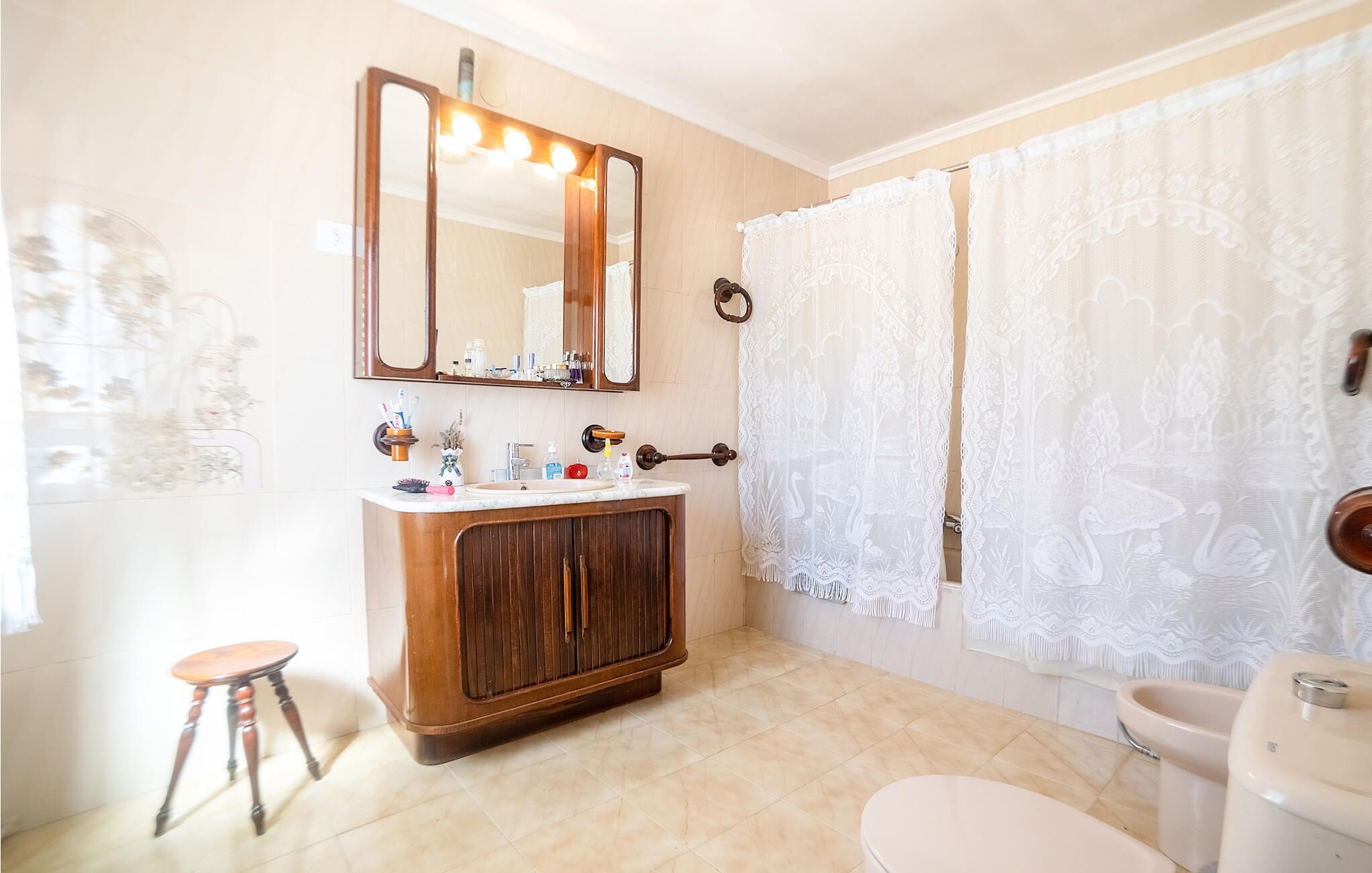 Une salle de bain avec un meuble-lavabo en bois, un grand miroir, des toilettes et un rideau de douche.