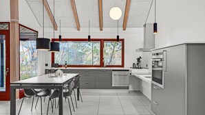 A modern kitchen with a dining area, large windows, and a view of trees. - Gorgeous home in Grenaa with WiFi (Grenaa)
