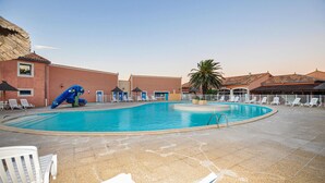 Ein Swimmingpool mit Liegestühlen und einer Rutsche, umgeben von Gebäuden mit Ziegeldächern.