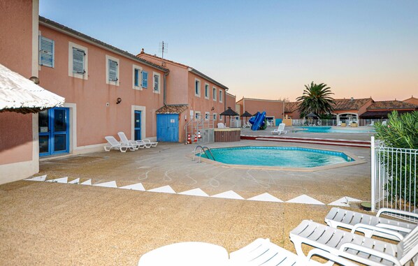 A pool area with multiple pools, lounge chairs, and a building with blue shutters. - Pet friendly home in Le Barcarès (Le Barcarès)