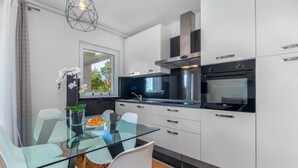 Eine moderne Küche mit weißen Schränken, einem Glastisch und einem eingebauten Backofen.