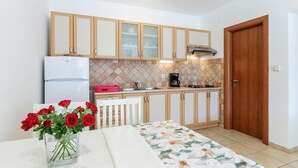 Eine kleine Küche mit Holzschränken, einem weißen Kühlschrank, einer Kaffeemaschine und einer Tür.
