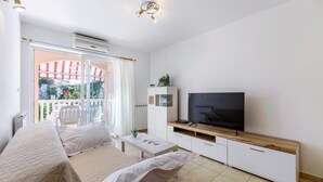 Ein modernes Wohnzimmer mit Sofa, Fernseher und Balkon mit Blick.