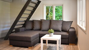A modern living room with a sectional sofa, a white coffee table, and a small plant. A wooden staircase is visible to the left. - 2 bedroom amazing home in Fjälkinge (Fjälkinge)