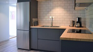 A modern kitchen with a built-in refrigerator, a sink with a faucet, a coffee maker, and a kettle on the countertop. - 2 bedroom amazing home in Fjälkinge (Fjälkinge)