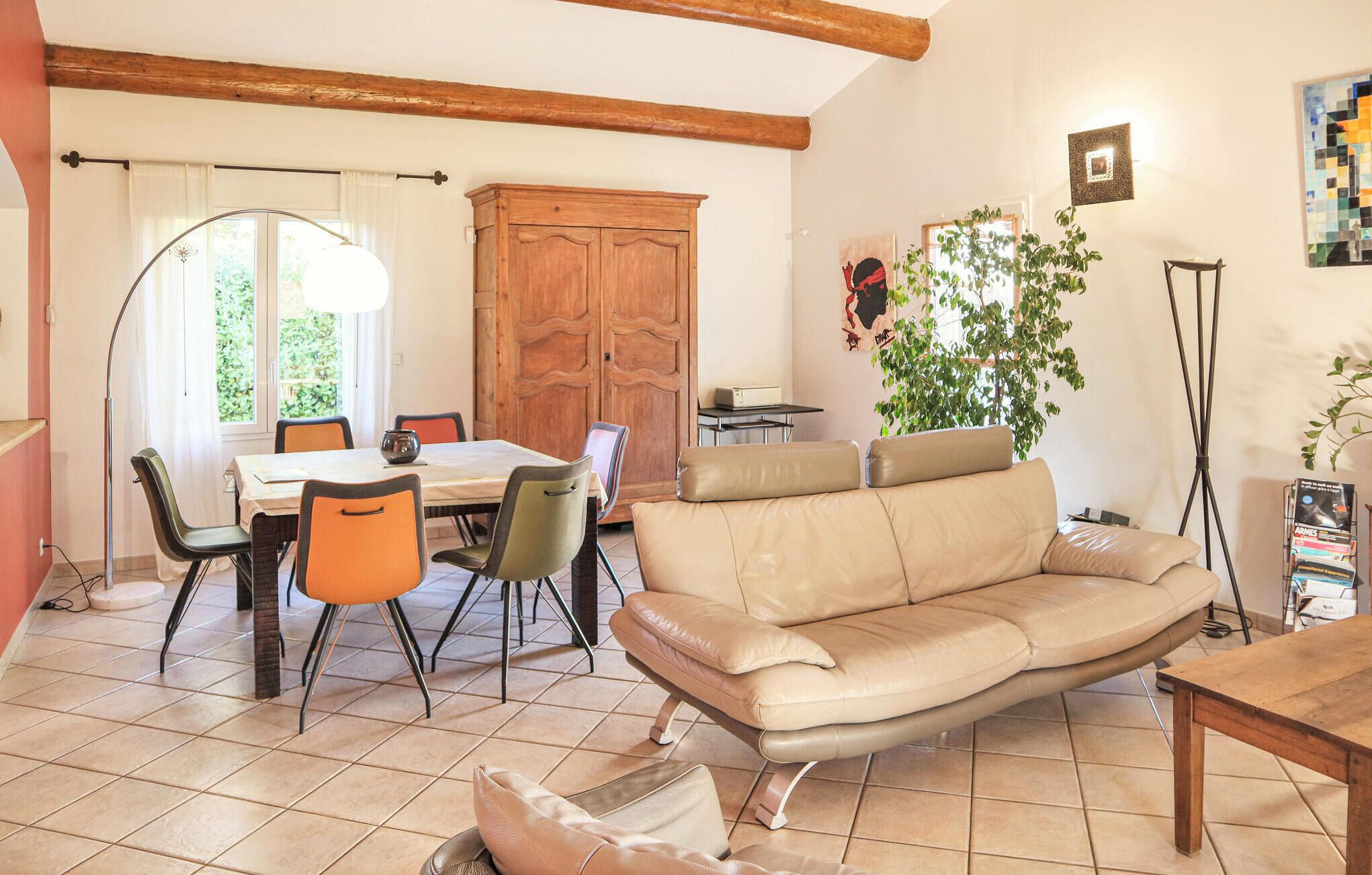 A dining area with a wooden table and chairs, a sofa, and a potted plant.