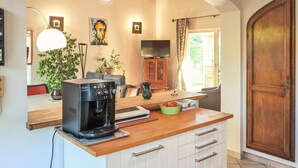 Una cucina con una macchina da caffè, una televisione e un armadietto in legno.