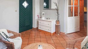 Una habitación con puerta verde, cómoda blanca y mobiliario de mimbre.