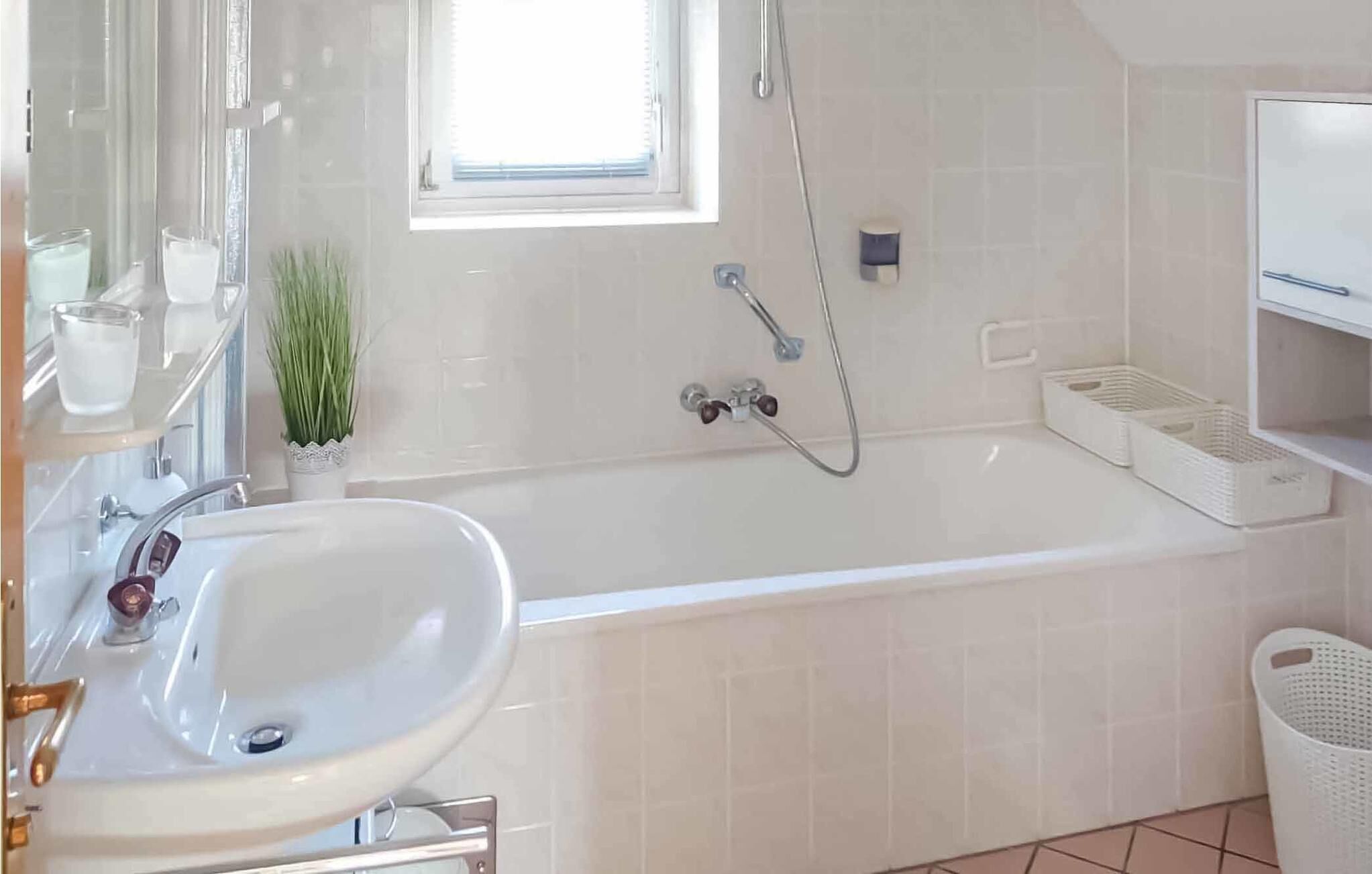 A modern bathroom with a white bathtub, a sink, and a window providing natural light.