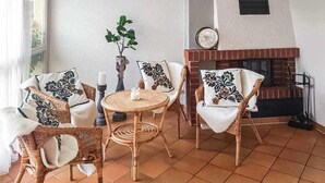 Una sala de estar acogedora con mobiliario de mimbre, una mesa redonda y una chimenea.