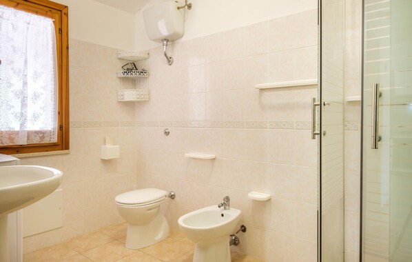 A bathroom with a toilet, bidet, sink, and a glass shower enclosure. - Amazing home in Torre dei Corsari (Torre dei Corsari)