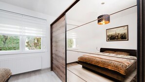 A bedroom with a bed, a cityscape painting, and a window with blinds. - Cozy home in Donji Andrijevci (Donji Andrijevci)