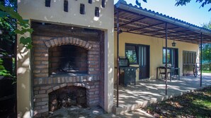 A brick fireplace, outdoor grill, and covered patio area with a table and chairs. - Cozy home in Donji Andrijevci (Donji Andrijevci)