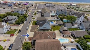 An aerial view of a residential area with houses, a swimming pool, and a beach in the background. - FABULOUS BEACH HOUSE- 7 Bedrooms,Heated Pool,12 BeachBadges,9 Car Driveway (Point Pleasant Beach)