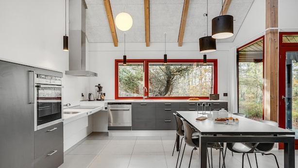 A modern kitchen with a large window, a dining area with a table and chairs, and a built-in oven.