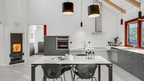 A modern kitchen with a central island, two pendant lights, a built-in oven, and a stove.