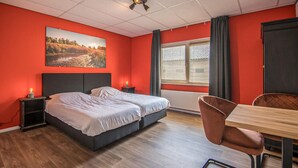 A hotel room with two beds, a wooden dining table, and a window with blinds. - 4 bedroom gorgeous home in Den Ham (Den Ham)