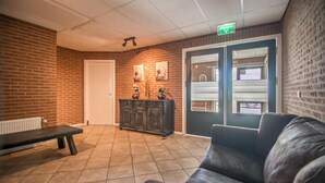 A lobby with a brick wall, a reception desk, a bench, a sofa, and a door with a window. - 4 bedroom gorgeous home in Den Ham (Den Ham)
