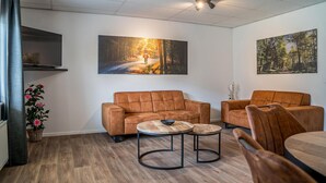 A modern living room with a sofa set, two round coffee tables, and two paintings on the walls. - 4 bedroom gorgeous home in Den Ham (Den Ham)