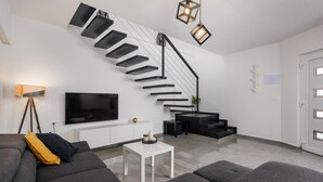 A modern living room with a staircase, a flat-screen TV, and a minimalist design. - Beautiful home in Zuzici (Zuzici)
