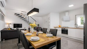 A modern kitchen with white cabinets, a built-in oven, and a window. - Beautiful home in Zuzici (Zuzici)