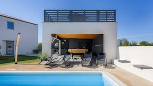 A modern outdoor pool area with a built-in bar and lounge chairs. - Beautiful home in Zuzici (Zuzici)