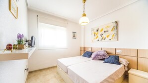 A hotel room with a bed, a small desk, a window, and a painting on the wall. - 2 bedroom beach front apartment in Cabanes (Cabanes)
