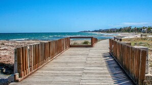 A wooden boardwalk leading to a beach with a clear view of the ocean and distant buildings. - 2 bedroom beach front apartment in Cabanes (Cabanes)