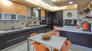 Una cocina moderna con muebles oscuros, encimera blanca y sillas naranjas.