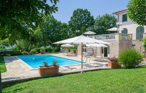 Un jardin avec une piscine, un espace salon extérieur et un bâtiment en pierre.