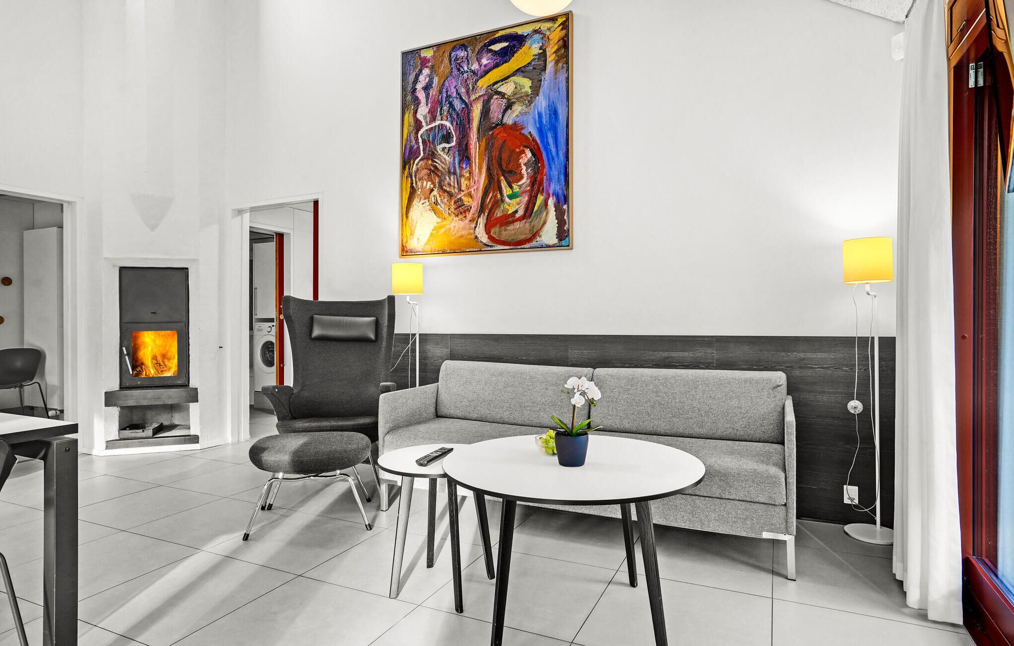 Un salon moderne avec un canapé gris, une table basse ronde et un tableau accroché au mur.
