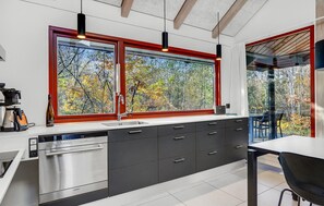 A modern kitchen with a large window, stainless steel appliances, and a view of autumn trees. - Cozy home in Grenaa with WiFi (Grenaa)
