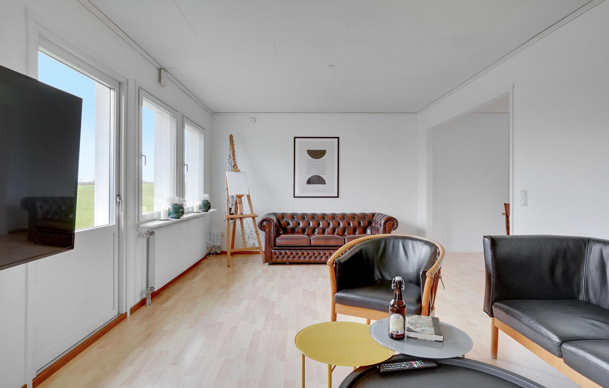 Un salon spacieux doté d’une grande fenêtre, d’une cheminée, d’un canapé en cuir, d’une table basse et d’un téléviseur.
