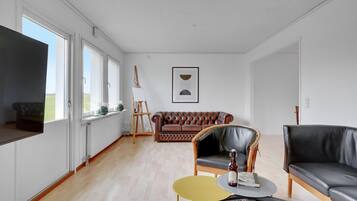 Un salon spacieux doté d’une grande fenêtre, d’une cheminée, d’un canapé en cuir, d’une table basse et d’un téléviseur.