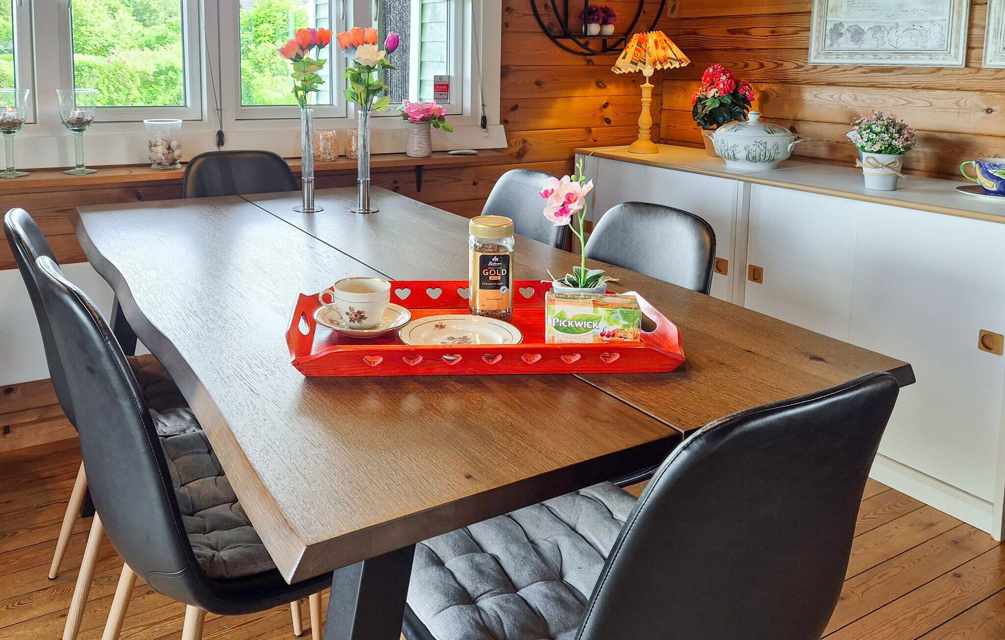 Une table de salle à manger en bois sur laquelle se trouve un plateau avec une tasse, un bocal et une boîte de biscuits Pickwick.
