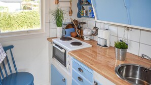 A compact kitchen with a stove, sink, and blue cabinets. - 2 bedroom amazing home in Kolmården (Kolmården)