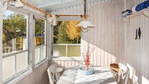A cozy room with a round table, white chairs, a window with a view of trees, and a hanging lamp. - 2 bedroom amazing home in Kolmården (Kolmården)