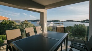 Een balkon met een tafel en stoelen met uitzicht op water en heuvels.