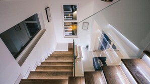 Een trap met houten treden en een glazen balustrade, die leidt naar een plateau met uitzicht op het interieur.