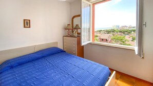 Ein Schlafzimmer mit einem Bett, einem Schminktisch, einem Spiegel und einem Fenster mit Blick auf die Stadt.