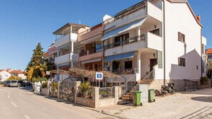 Um edifício residencial com várias andares, sacadas, portão e céu claro.