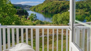 A balcony with a view of a lake surrounded by greenery. - 4 bedroom beautiful home in Farsund (Farsund)