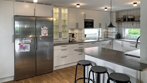 A modern kitchen with stainless steel appliances, white cabinetry, and a central island with stools.