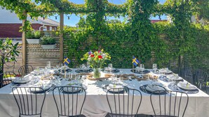 An outdoor dining table set with white tablecloths, black chairs, and Swedish flags.