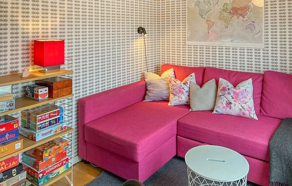 Un accogliente soggiorno con un divano rosa, un tavolino bianco e una libreria piena di giochi da tavolo.